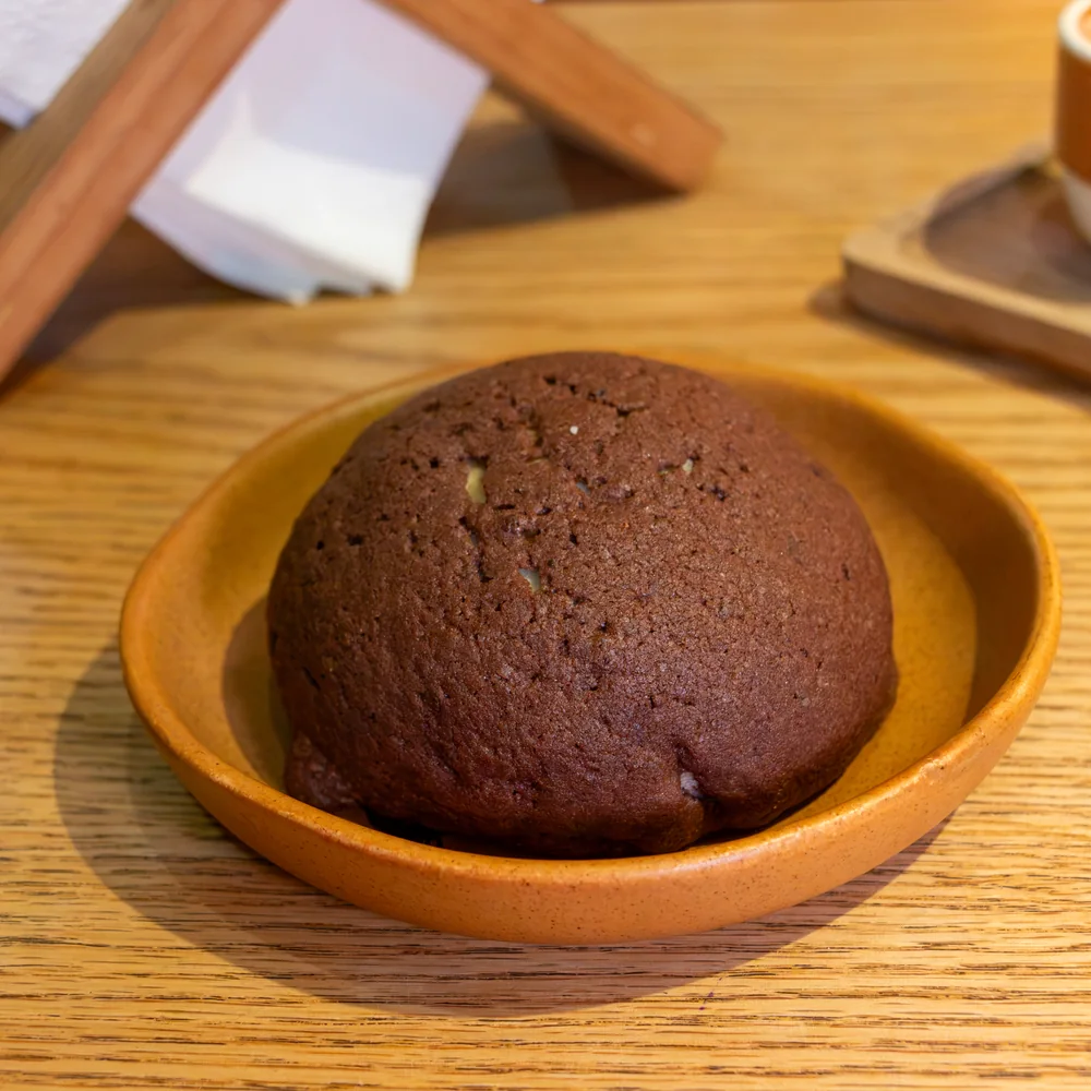 Concha de chocolate recién horneada, servida en plato de barro